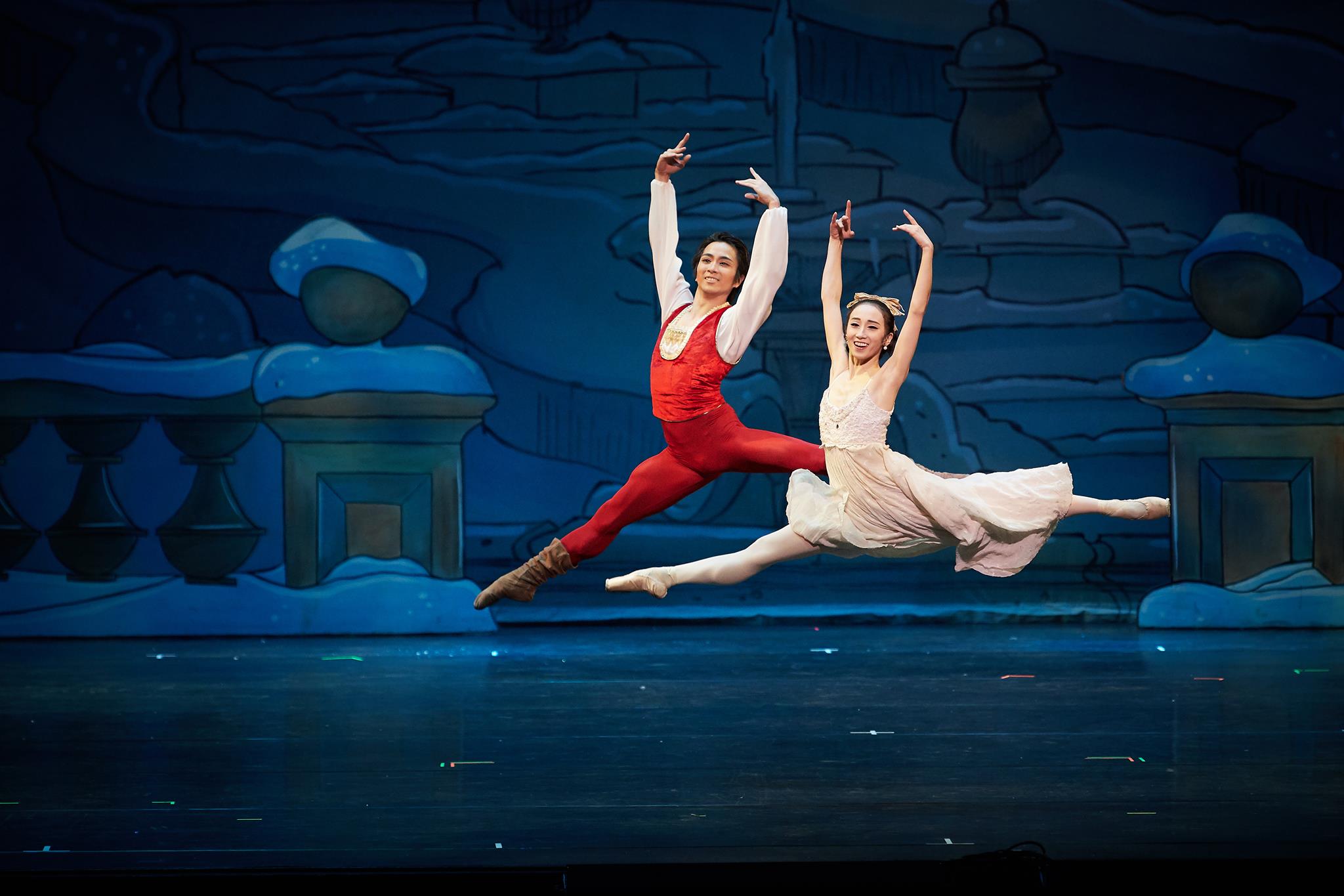 two dancers jumping in front of a snowy blue background